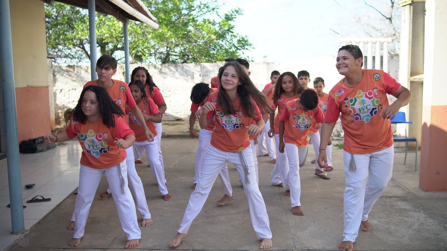 Crianças e educadores do FFC participam de uma roda de capoeira ao ar livre.
