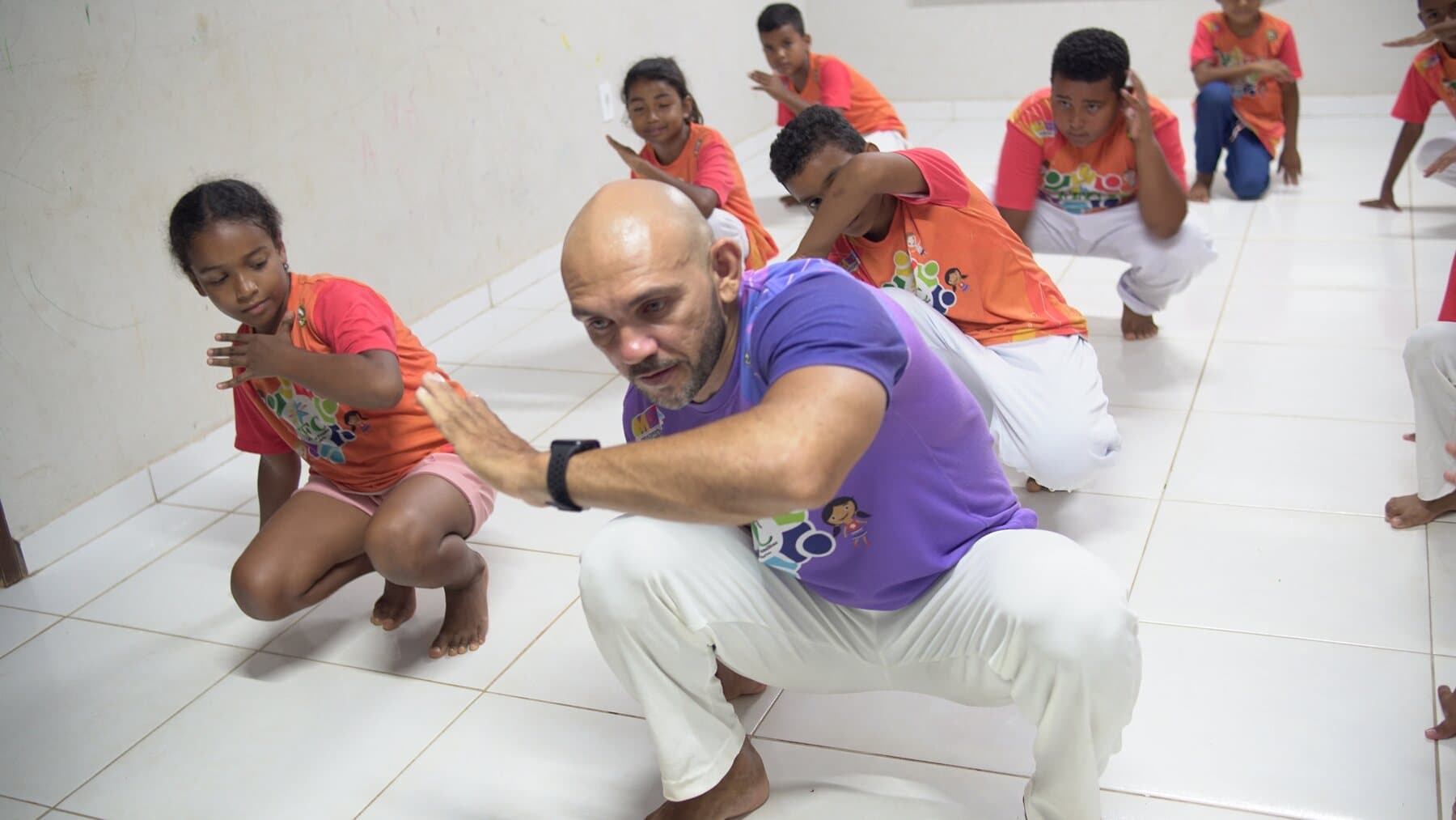 Educador orienta crianças do FFC durante uma vivência de capoeira.
