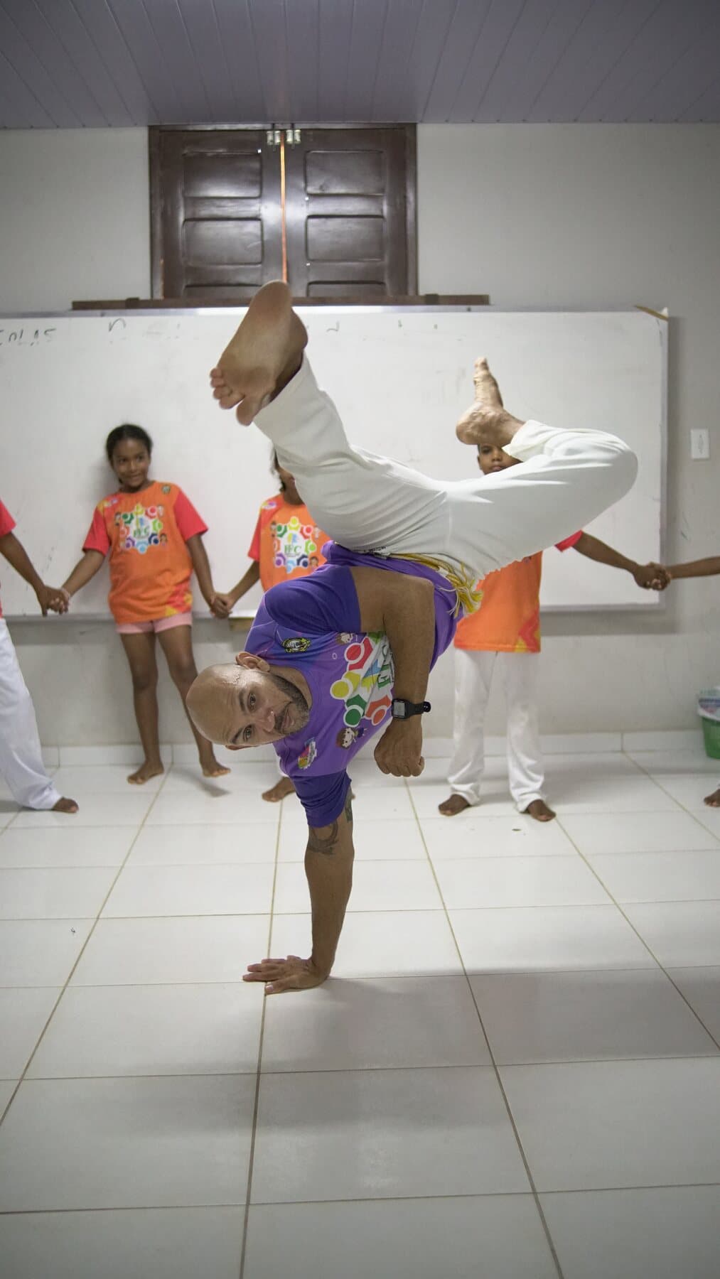 Educador executa um movimento de capoeira diante das crianças do FFC.