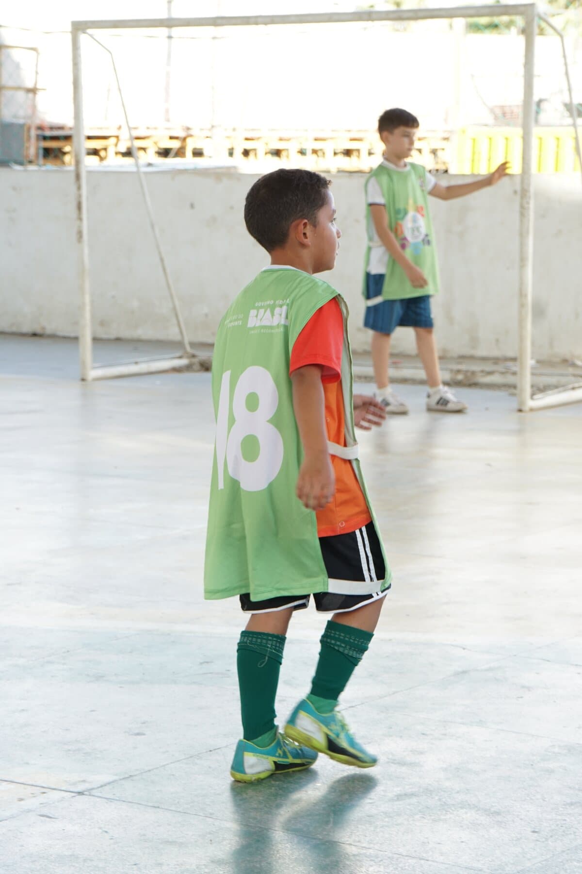 Criança com colete verde participa de uma atividade de futsal do FFC.