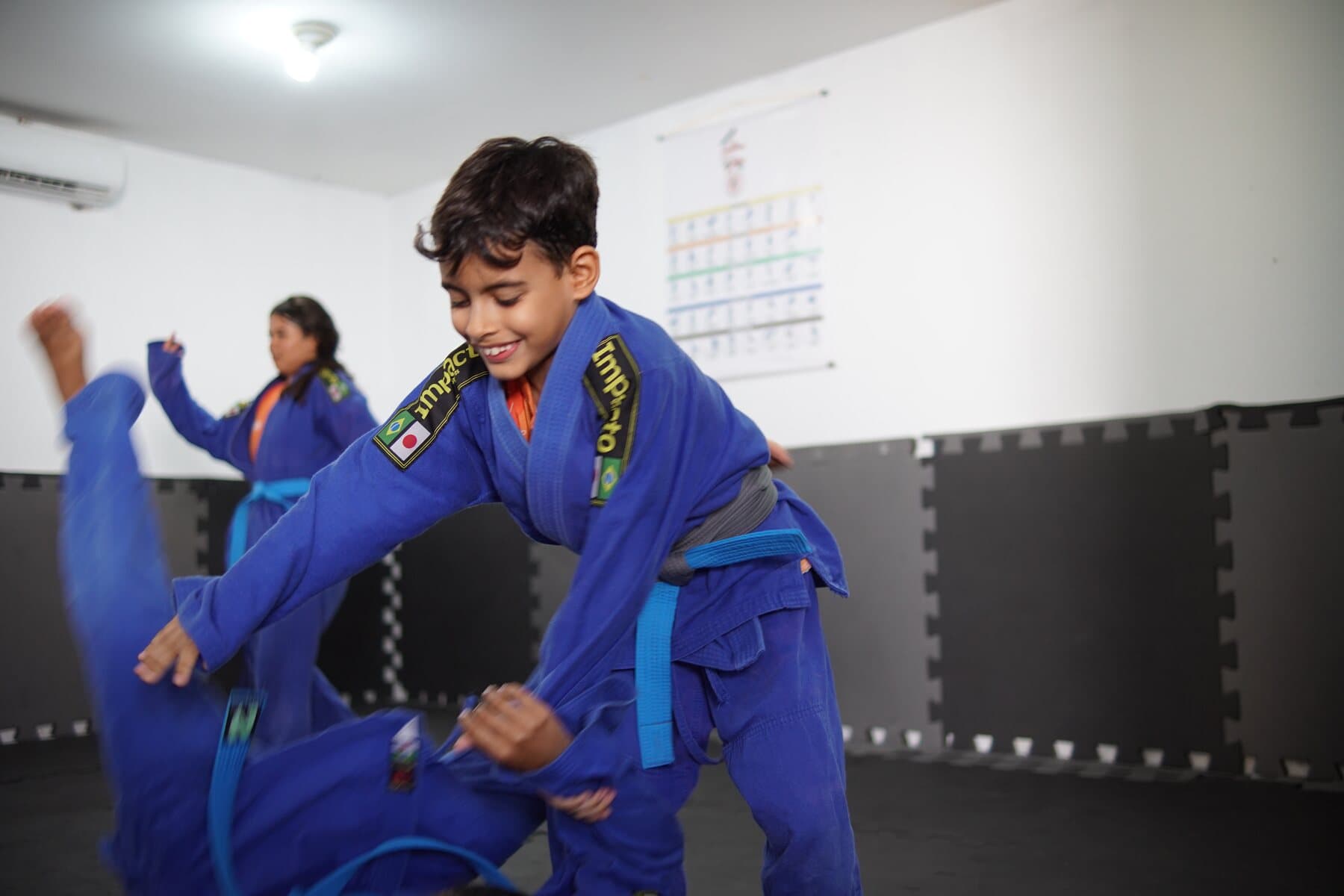 Crianças do FFC praticam judô no tatame durante uma oficina esportiva.