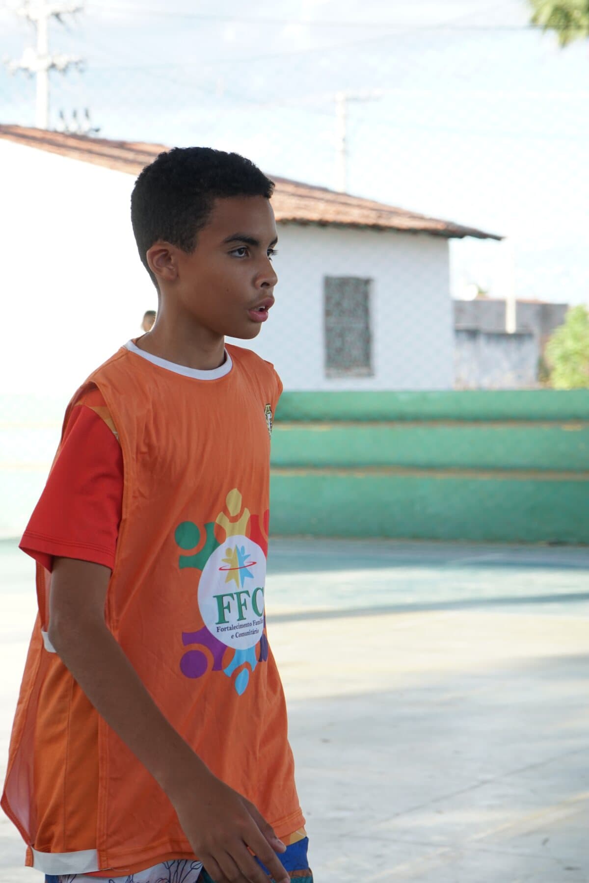 Criança de uniforme laranja acompanha uma atividade de queimada do FFC.