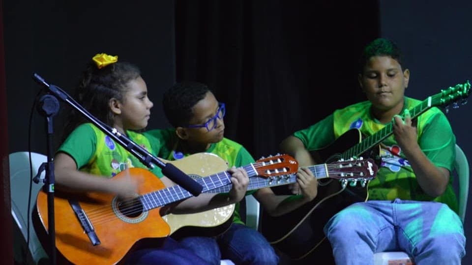 Crianças e adolescentes do FFC tocando violão em uma apresentação musical.