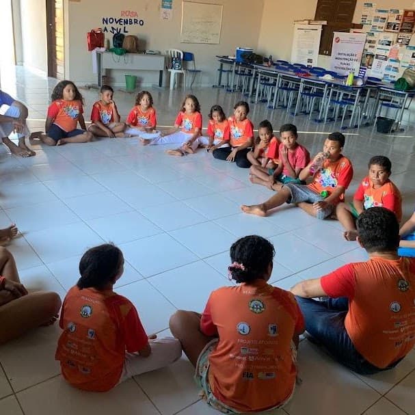 Crianças e adolescentes do FFC sentados em roda durante atividade comunitária.